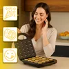 A woman is smiling while holding an open waffle maker with mini waffles inside. There are three graphic icons on the left side of the image. Voir les images du produit