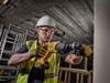 A construction worker is using a DeWALT hammer drill on a concrete surface. Náhled obrázku produktu