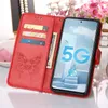 A red flip phone case with card slots and a butterfly embossed design is shown open, displaying a smartphone with a "5G" graphic on its screen. Produktbild-Vorschau