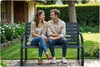 A couple sits on a park bench in a garden setting. Produktbild-Vorschau