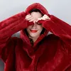 A woman wearing a red hoodie blanket, covering her eyes with her hands. Produktbild-Vorschau