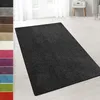A dark gray shaggy rug is displayed on a light-colored floor in a room with white curtains and a white side table. A strip of color swatches is visible on the left side of the image. Náhled obrázku produktu