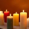 Several lit pillar candles of various colors are arranged on a surface. Voir les images du produit