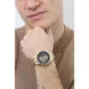A man wearing a brown sweater is showing off a gold watch on his wrist. Voir les images du produit