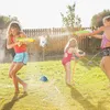 Three children playing with water guns and a sprinkler in a backyard on a sunny day. Produktbild-Vorschau