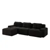 A black modular L-shaped sofa with an ottoman, shown from a side-angle. Produktbild-Vorschau