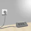 A power strip with multiple outlets and a wall socket with a plug are shown on a wooden surface against a gray wall. Produktbild-Vorschau