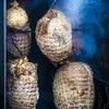 Several netted meat rolls are hanging in a smoker, with smoke visible. Produktbild-Vorschau