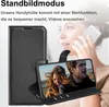 A black flip case for a smartphone is shown open, with a phone displaying a couple on its screen. A woman is partially visible in the background, holding a phone. Produktbild-Vorschau