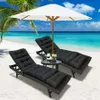 Two black lounge chairs with cushions are set up on a sandy beach next to the ocean, with a white umbrella providing shade. Náhled obrázku produktu