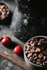 A close-up of a speckled black coffee maker with coffee beans and cherries. Náhľad obrázku produktu