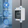 A white electrical enclosure with a transparent cover is mounted on a tiled wall, with a black cable entering from the top and exiting from the bottom. To the left, there are three blue circular icons with white graphics and text describing product feature Produktbild-Vorschau