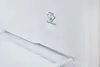 A close-up view of the interior of a white appliance, likely a refrigerator or freezer, showing a shelf and a sticker with instructions. Produktbild-Vorschau