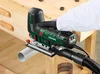 A person is using a green and black jigsaw on a wooden workbench. Produktbild-Vorschau