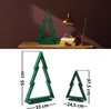 A collage showing two green wooden Christmas trees, one larger than the other, with dimensions indicated. The top part of the collage shows a larger green Christmas tree on a wooden table next to a stack of books and a lamp. Anteprima dell’immagine prodotto