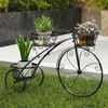 A black metal bicycle-shaped plant stand holding three potted plants, placed on grass in an outdoor setting. Anteprima dell’immagine prodotto