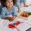 A young child is lying on a white surface, playing with colorful wooden beads. Podgląd zdjęcia produktu