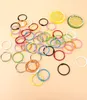 A collection of colorful metal binder rings scattered on a light peach background, with two decorative lemon slices in the upper right corner. Produktbild-Vorschau
