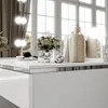 A vanity table with various beauty products and a floral arrangement, set against a window background with natural light. Produktbild-Vorschau