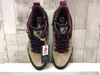 A pair of beige hiking boots with burgundy accents, displayed on a white shelf against a wood-planked background. Produktbild-Vorschau