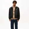 A man wearing a black jacket over a tan hoodie and blue jeans, standing against a white background. Voir les images du produit
