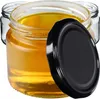 Three glass jars filled with honey, one with a black lid placed next to it. Produktbild-Vorschau