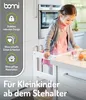 A young girl standing in a kitchen, looking at items on a counter. Produktbild-Vorschau