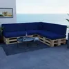 A sectional sofa made of wooden pallets with dark blue cushions is placed on a balcony overlooking the ocean. Produktbild-Vorschau