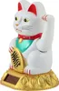 A white Maneki-neko (lucky cat) figurine with a waving arm, holding a gold coin, on a gold base with a solar panel. Produktbild-Vorschau