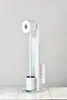 A white toilet brush and toilet paper holder stand on a marble-like surface against a light gray wall. Podgląd zdjęcia produktu