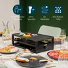 A raclette grill set up on a table with food and drinks, set for a meal. Produktbild-Vorschau