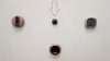 Several smart doorbells and cameras are mounted on a white wall, with a red arrow pointing to the central camera. Produktbild-Vorschau