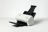 A white Brother document scanner is shown on a white surface against a white background. Voir les images du produit