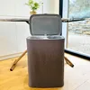 A laundry hamper with its lid open, placed on a wooden floor in a room with natural light coming from a large window. Produktbild-Vorschau