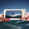 Hands holding a waterproof phone case with a surfer on a wave displayed on the screen, with the case partially submerged in water. Produktbild-Vorschau