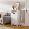 A white storage cabinet with a drawer and two doors is placed next to a gray sofa and a door. An umbrella stand with umbrellas is next to the cabinet. Náhled obrázku produktu