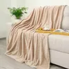 A beige blanket draped over a sofa with a plant and a tray with a cup and book. Anteprima dell’immagine prodotto
