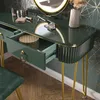 A close-up view of a dark green vanity table with gold accents, showing an open drawer with a decorative box inside, and makeup items on the surface. Náhľad obrázku produktu
