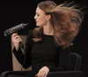 A woman is using a hairdryer to style her hair. Podgląd zdjęcia produktu