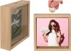 A collage showing a wooden money box with a picture inside and a hand inserting a coin into a similar money box. Produktbild-Vorschau