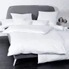 A neatly made bed with white bedding and a gray headboard. Produktbild-Vorschau