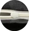 A close-up view of a zipper on black fabric. Produktbild-Vorschau