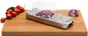 A kitchen utensil for chopping onions and vegetables, placed on a wooden cutting board next to cherry tomatoes and a piece of red onion. Náhled obrázku produktu