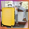 A person is sitting next to a yellow suitcase. Anteprima dell’immagine prodotto