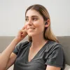 A woman wearing earbuds and listening to something. Produktbild-Vorschau