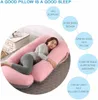 A woman is sleeping on a U-shaped pregnancy pillow in a bedroom setting. Náhled obrázku produktu