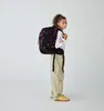 A young girl wearing a backpack and standing against a white background. Anteprima dell’immagine prodotto