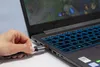 A hand is plugging an HDMI cable into a laptop that is displaying a video game. Podgląd zdjęcia produktu