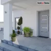 A modern house entrance with a gray door, a white pillar, and potted plants on a gray tiled patio. Voir les images du produit