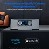 A modern stereo system is shown on a dark surface, with a couch in the background. The image highlights streaming service compatibility. Produktbild-Vorschau